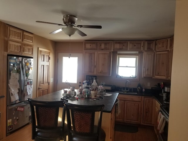 kitchen with a center island, sink, stainless steel refrigerator, range with electric stovetop, and light wood-type flooring