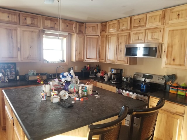 kitchen with decorative light fixtures, an island with sink, a kitchen breakfast bar, and appliances with stainless steel finishes