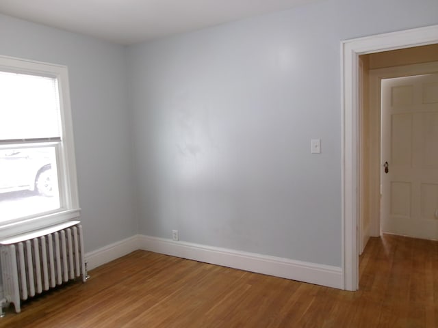 spare room featuring radiator and wood-type flooring