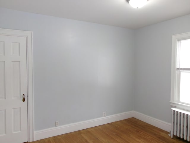 empty room featuring radiator and hardwood / wood-style floors