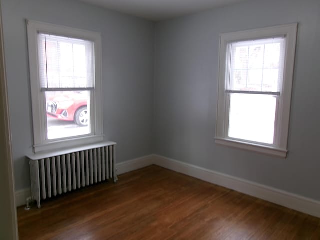 unfurnished room featuring radiator and dark hardwood / wood-style floors