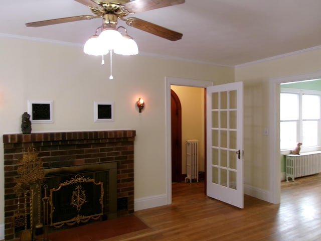 unfurnished living room featuring hardwood / wood-style flooring, ornamental molding, and radiator heating unit