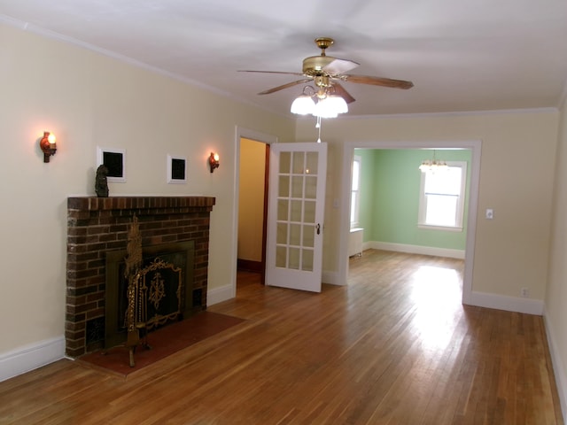 unfurnished living room with crown molding, ceiling fan, wood-type flooring, and a fireplace