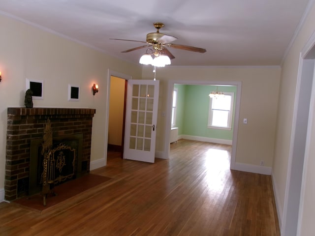 unfurnished living room featuring a brick fireplace, wood-type flooring, ornamental molding, and ceiling fan