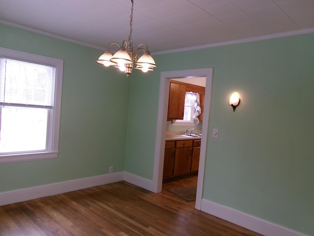 unfurnished dining area featuring crown molding, sink, a chandelier, and dark hardwood / wood-style flooring