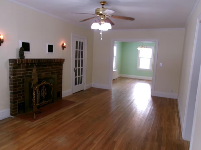 unfurnished living room with ceiling fan, ornamental molding, a fireplace, and wood-type flooring