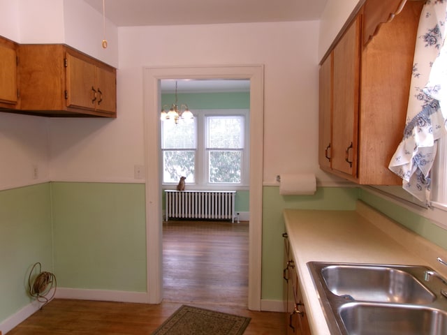 kitchen with sink, an inviting chandelier, hardwood / wood-style floors, hanging light fixtures, and radiator heating unit