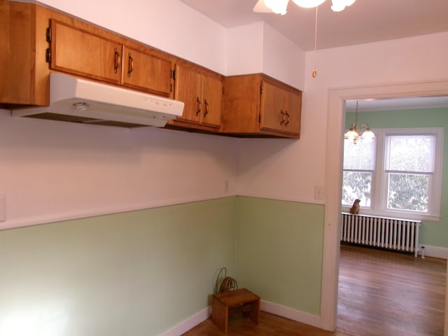 kitchen featuring dark hardwood / wood-style floors, decorative light fixtures, radiator, and a notable chandelier