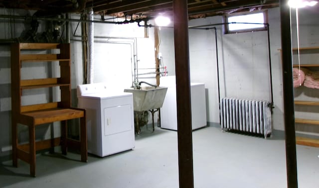 basement featuring radiator, sink, and washer and dryer