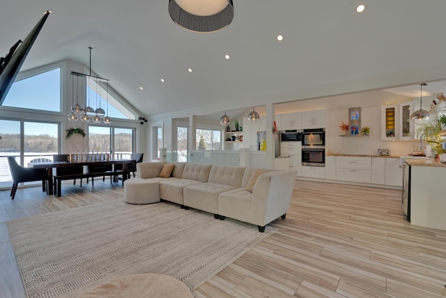 living room with a notable chandelier, sink, high vaulted ceiling, and light hardwood / wood-style floors