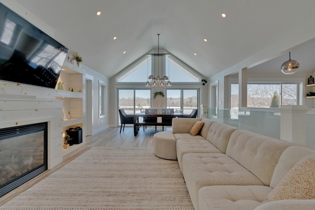 living room with plenty of natural light, a chandelier, high vaulted ceiling, and light hardwood / wood-style floors