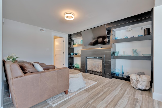 living room with built in features and light wood-type flooring
