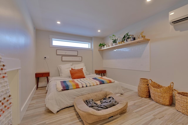 bedroom with a wall mounted air conditioner and light hardwood / wood-style flooring