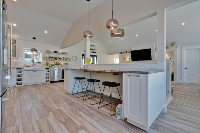 kitchen featuring pendant lighting, dark stone countertops, a kitchen breakfast bar, white cabinets, and kitchen peninsula