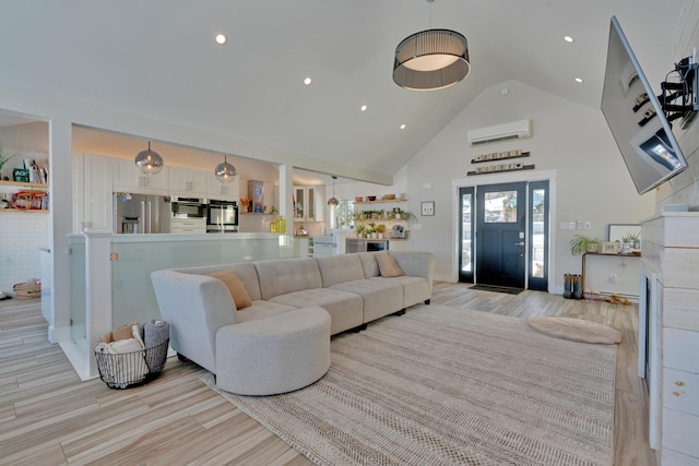living room featuring light hardwood / wood-style flooring, high vaulted ceiling, and an AC wall unit