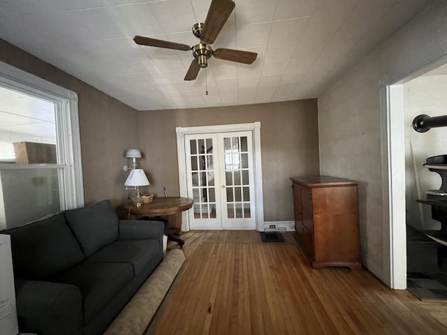 living room featuring ceiling fan, french doors, and wood-type flooring