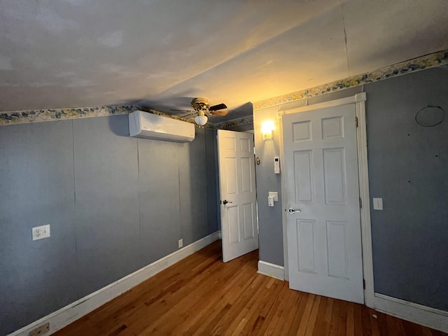 unfurnished bedroom featuring light hardwood / wood-style floors, ceiling fan, and a wall mounted AC