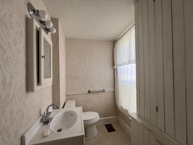 bathroom with vanity, toilet, a textured ceiling, and tile patterned flooring