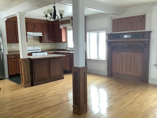 kitchen featuring white gas range, light hardwood / wood-style floors, a center island, and a chandelier