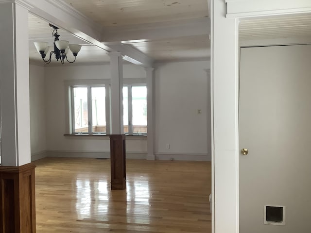 unfurnished room with decorative columns, light wood-type flooring, beamed ceiling, and a notable chandelier