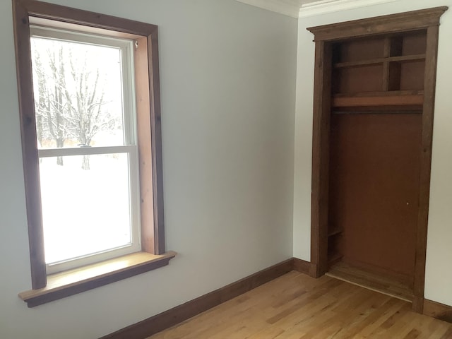 unfurnished bedroom with ornamental molding, light hardwood / wood-style flooring, and a closet