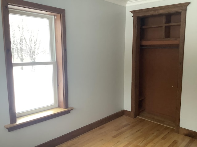 unfurnished bedroom featuring crown molding and light wood-type flooring