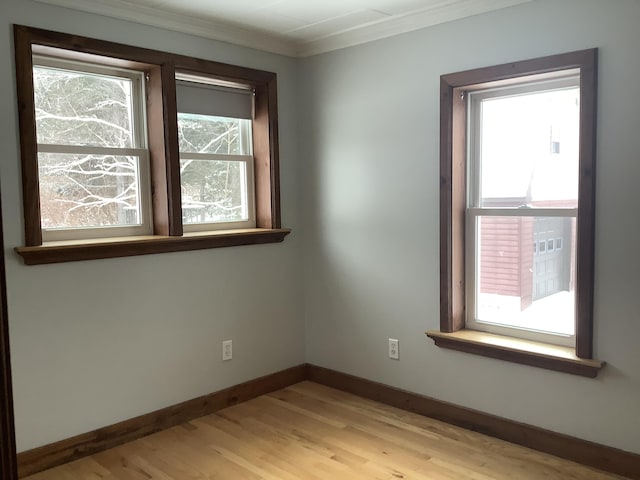 empty room featuring crown molding, a healthy amount of sunlight, and light hardwood / wood-style flooring