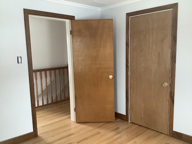 unfurnished bedroom with light hardwood / wood-style flooring, a closet, and ornamental molding