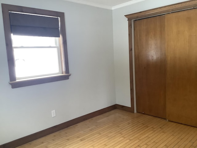 unfurnished bedroom with a closet, ornamental molding, and light hardwood / wood-style flooring