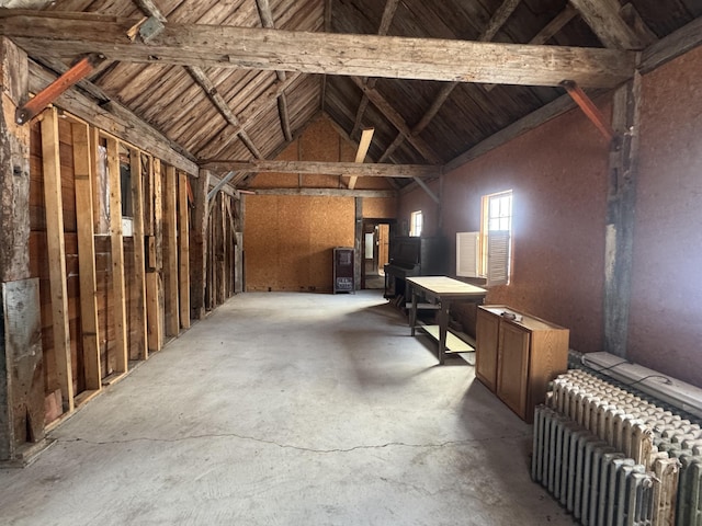 miscellaneous room featuring vaulted ceiling with beams, radiator heating unit, and concrete floors