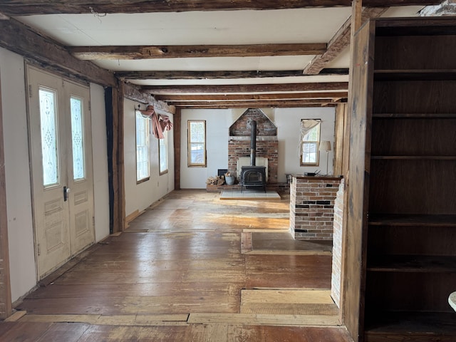 foyer with a wood stove, a wealth of natural light, and beam ceiling