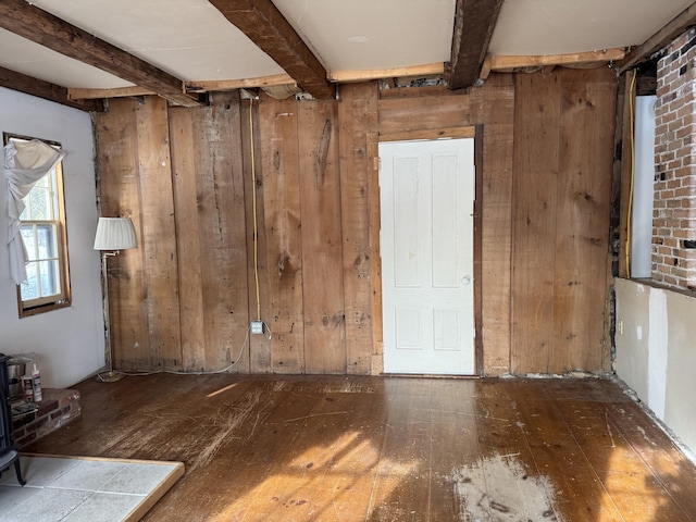 spare room with beamed ceiling, dark hardwood / wood-style floors, and wooden walls