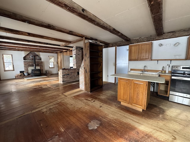 kitchen with stainless steel electric stove, a center island, a wood stove, and beam ceiling