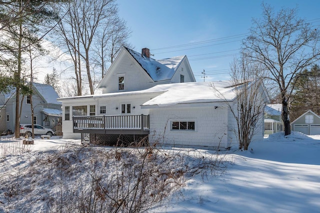 snow covered back of property with a wooden deck