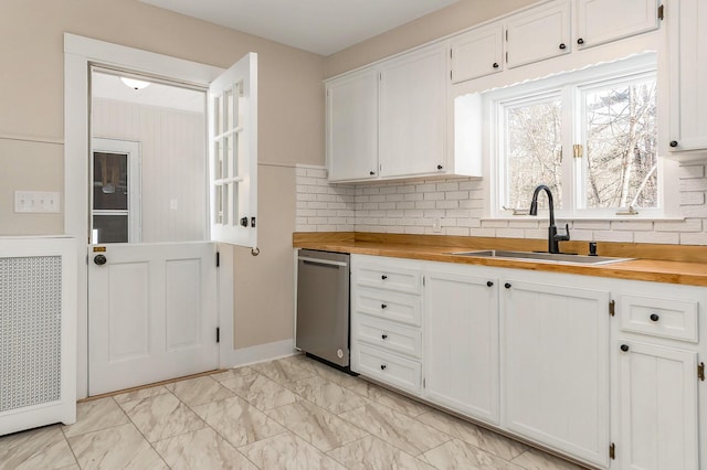 kitchen with butcher block countertops, sink, and white cabinets