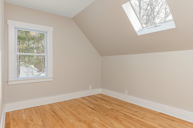 additional living space with wood-type flooring and lofted ceiling with skylight