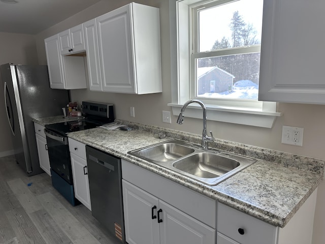 kitchen featuring light countertops, white cabinetry, a sink, light wood-type flooring, and black appliances