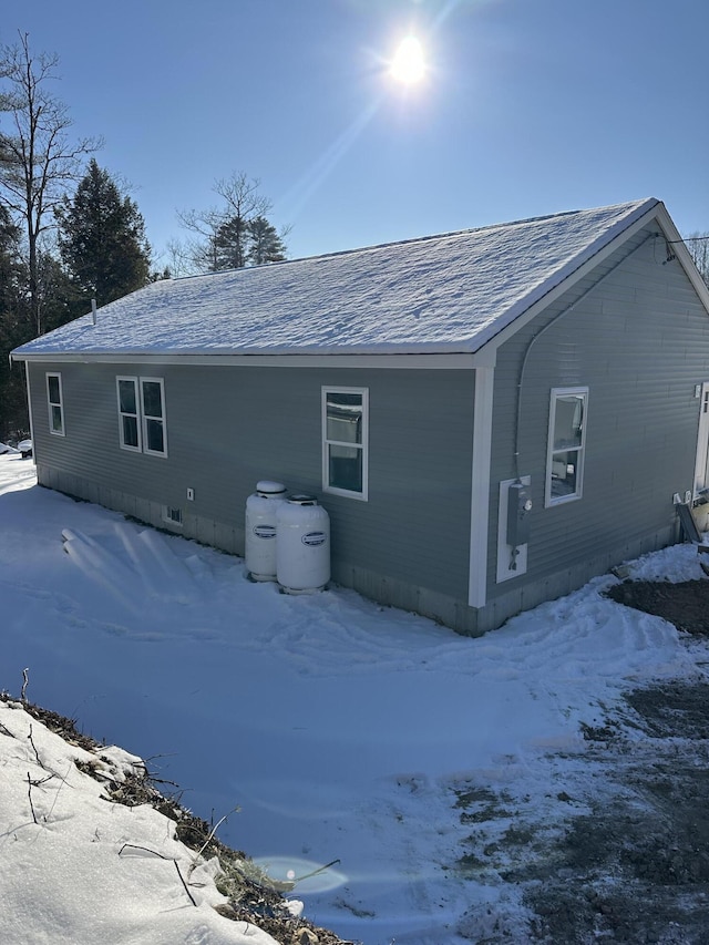 snow covered back of property with a shingled roof