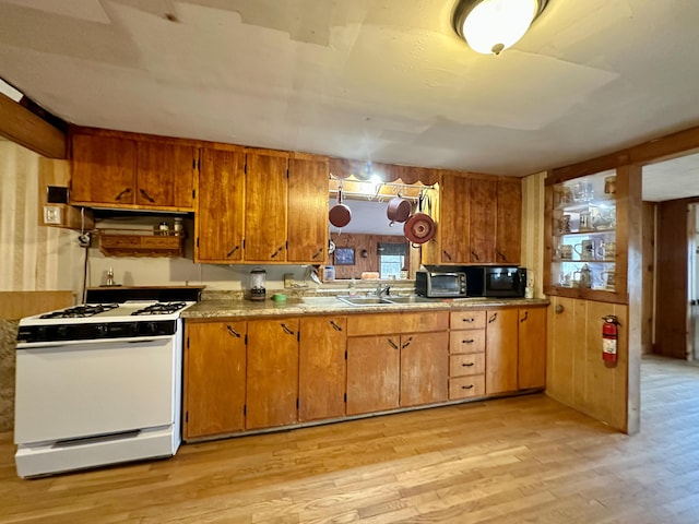 kitchen featuring sink, light hardwood / wood-style flooring, and white gas range oven