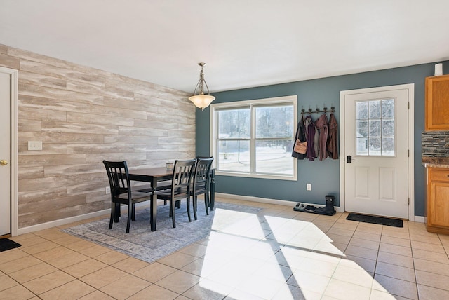 dining space featuring light tile patterned flooring and wooden walls