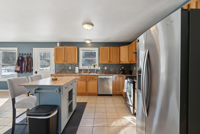 kitchen featuring sink, light tile patterned flooring, a healthy amount of sunlight, and appliances with stainless steel finishes