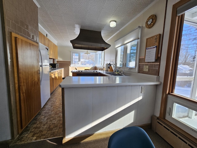 kitchen with kitchen peninsula, a baseboard radiator, crown molding, sink, and refrigerator