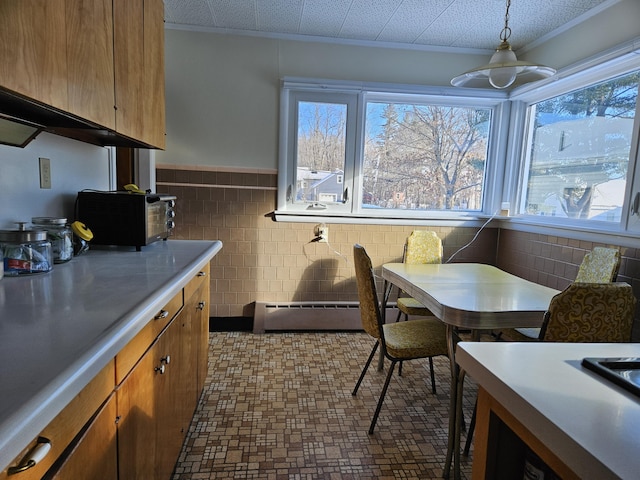 dining room with crown molding, a baseboard heating unit, and tile walls