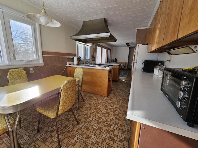 kitchen featuring ceiling fan, plenty of natural light, kitchen peninsula, and exhaust hood