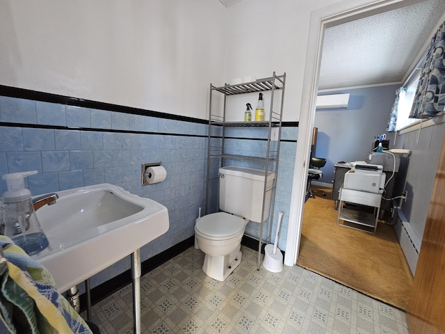 bathroom featuring baseboard heating, sink, tile walls, toilet, and a wall mounted AC