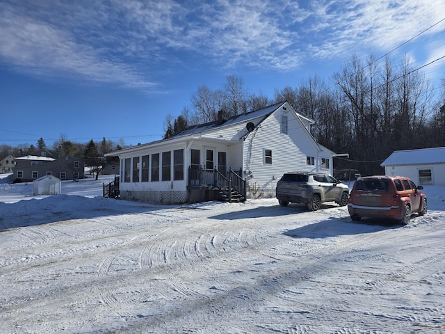 view of snowy exterior featuring a sunroom