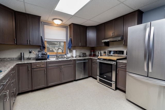 kitchen with sink, a paneled ceiling, dark brown cabinets, stainless steel appliances, and light stone countertops