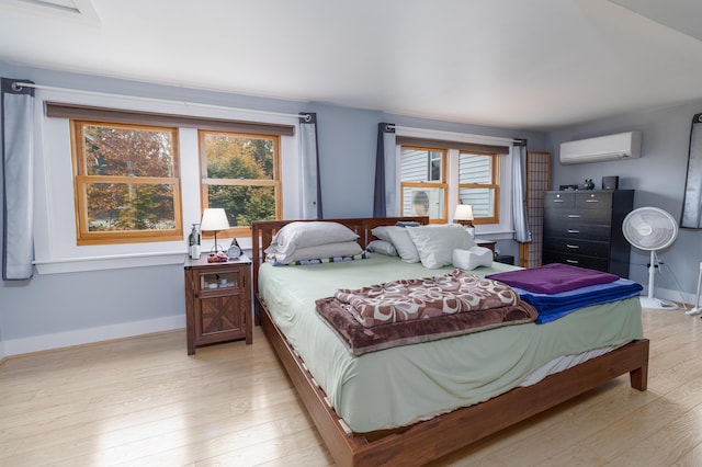 bedroom featuring a wall mounted AC and light wood-type flooring