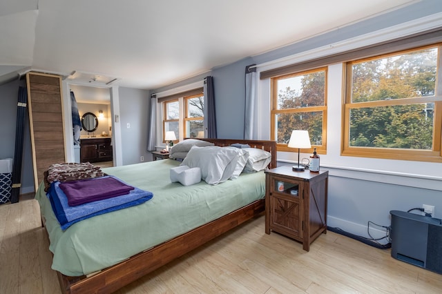 bedroom featuring light wood-type flooring and ensuite bath