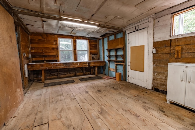 misc room featuring a wealth of natural light, light hardwood / wood-style flooring, and wood walls